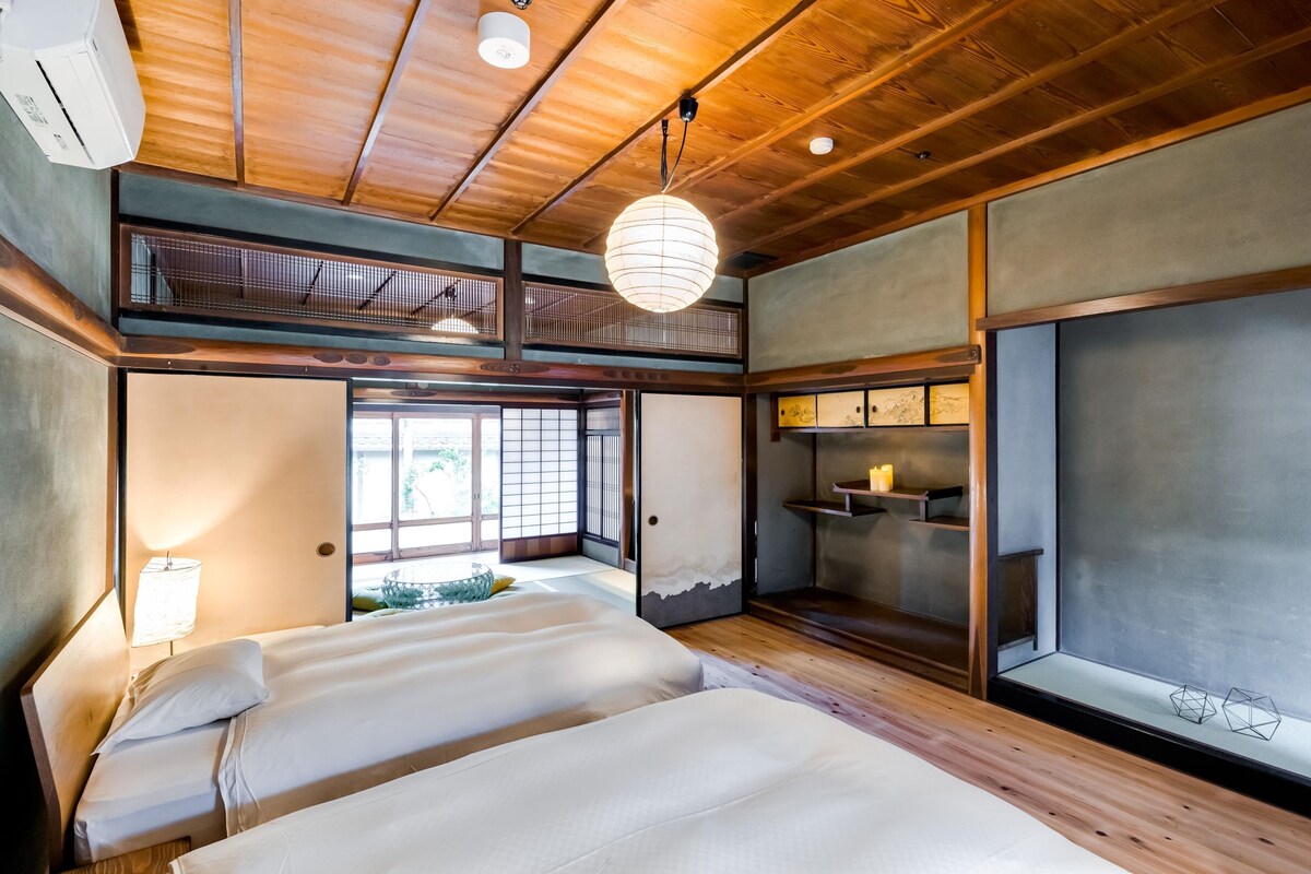 Una habitación tradicional japonesa con suelo de tatami, techo bajo y puertas correderas que dan a un balcón.
