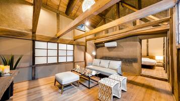 A cozy room with a wooden ceiling, a sofa, a coffee table, and a patterned ottoman.