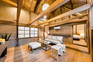 Una habitación acogedora con techo de madera, un sofá, una mesita de café y un reposapiés estampado.