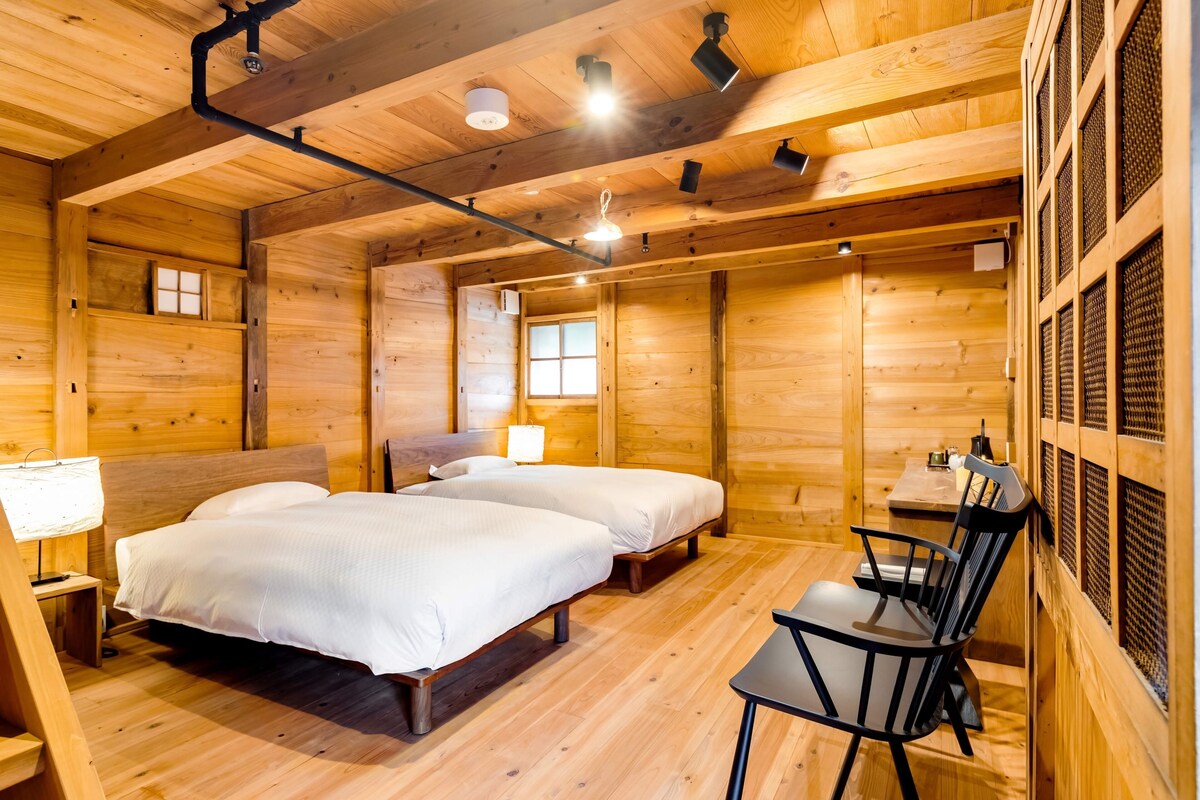 Una habitación de cabaña de madera con dos camas, una mesa y una silla.