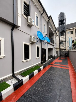A building with satellite dishes, a water tank, and a patterned walkway. - Grand 4BR Luxury Duplex near Airport – 15 mins from airport (Benin)