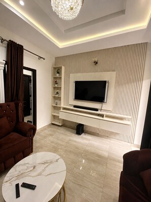 A modern living room with a flat-screen TV, a marble coffee table, and a brown sofa. - Grand 4BR Luxury Duplex near Airport – 15 mins from airport (Benin)