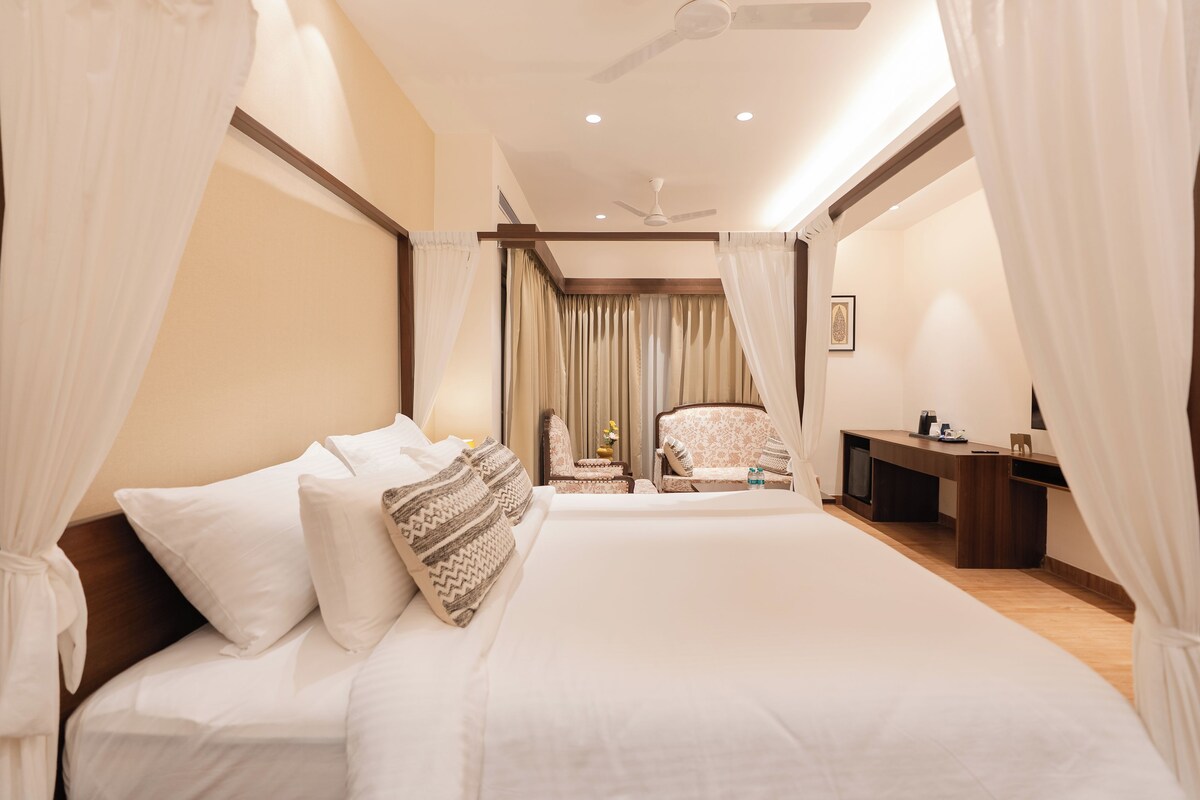Habitación de hotel con una cama grande, un escritorio, una silla y un ventilador de techo.