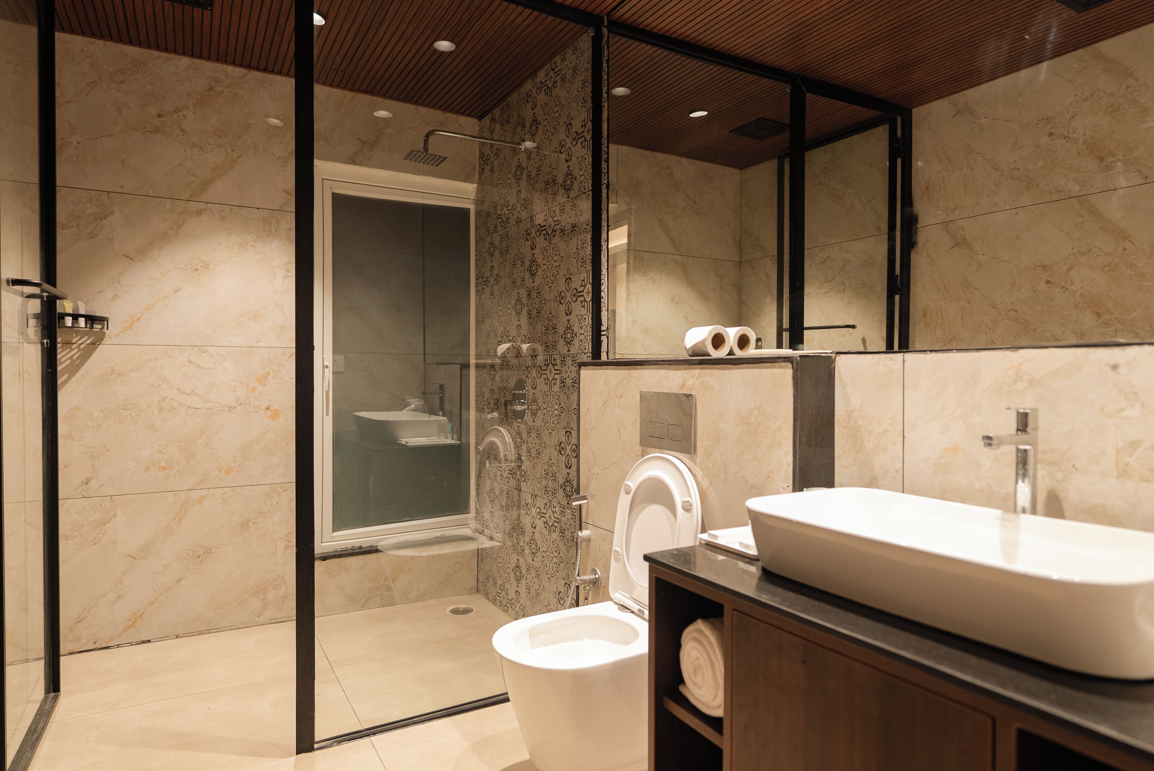 Un baño moderno con un espejo grande, un lavabo y un inodoro.