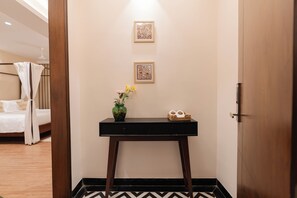 A hotel room with a bed, a bedside table with a vase of flowers, and two framed pictures on the wall. - Suites 16 - Financial District, Hyderabad (Hyderabad)