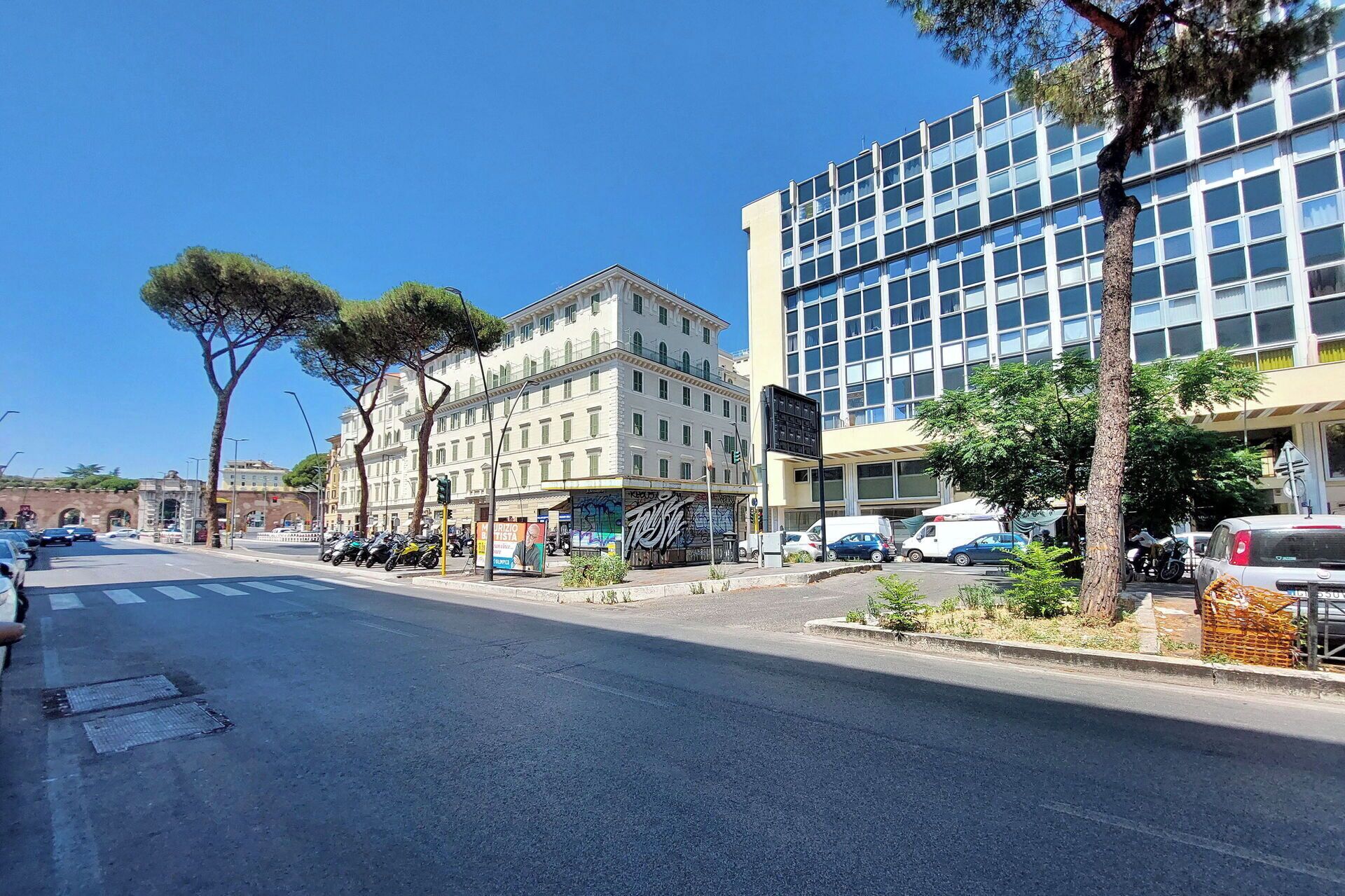 A street with buildings, trees, and parked cars.
