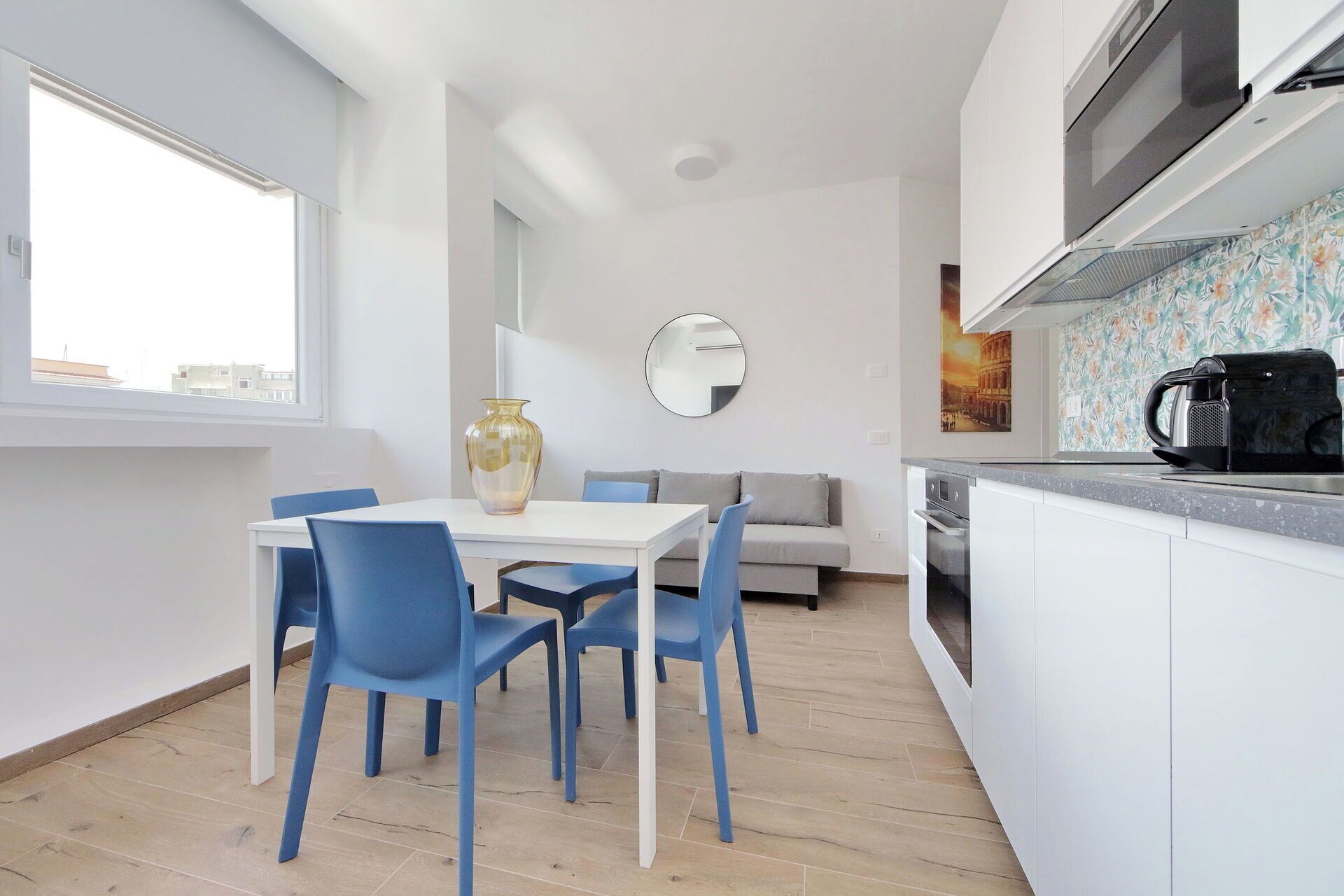 Una cocina moderna con gabinetes blancos, una cafetera negra y un salpicadero de azulejos.