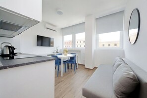 Eine moderne Küche mit Flachbildfernseher, einer Kaffeemaschine und einem Essbereich mit Tisch und Stühlen.