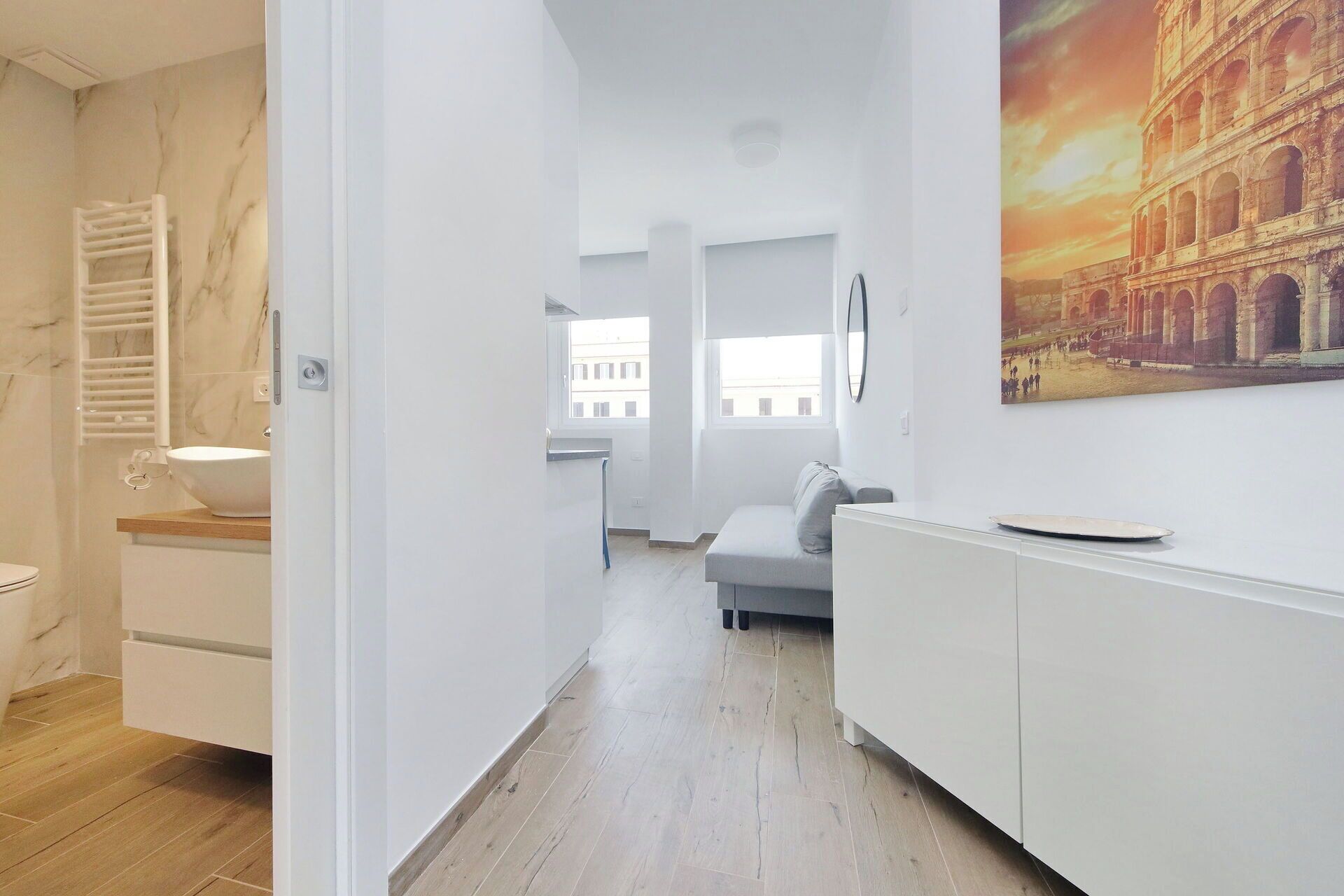 A modern bathroom with a white sink, a towel rack, and a wooden floor.