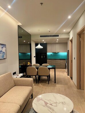 A modern living room with a sofa, a dining table with chairs, and a marble coffee table. - CMH Homestay A side - 5star standard (Halong City)