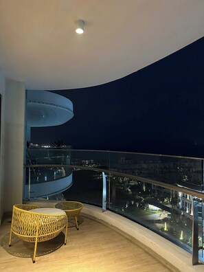 A balcony with a curved railing, a round wicker chair, and a second chair with a cushion. - CMH Homestay A side - 5star standard (Halong City)