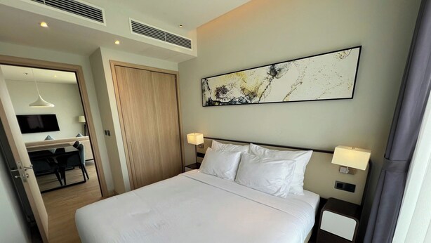 A hotel room with a bed, bedside lamps, a TV, a desk, and a chair. - CMH Homestay A side - 5star standard (Halong City)