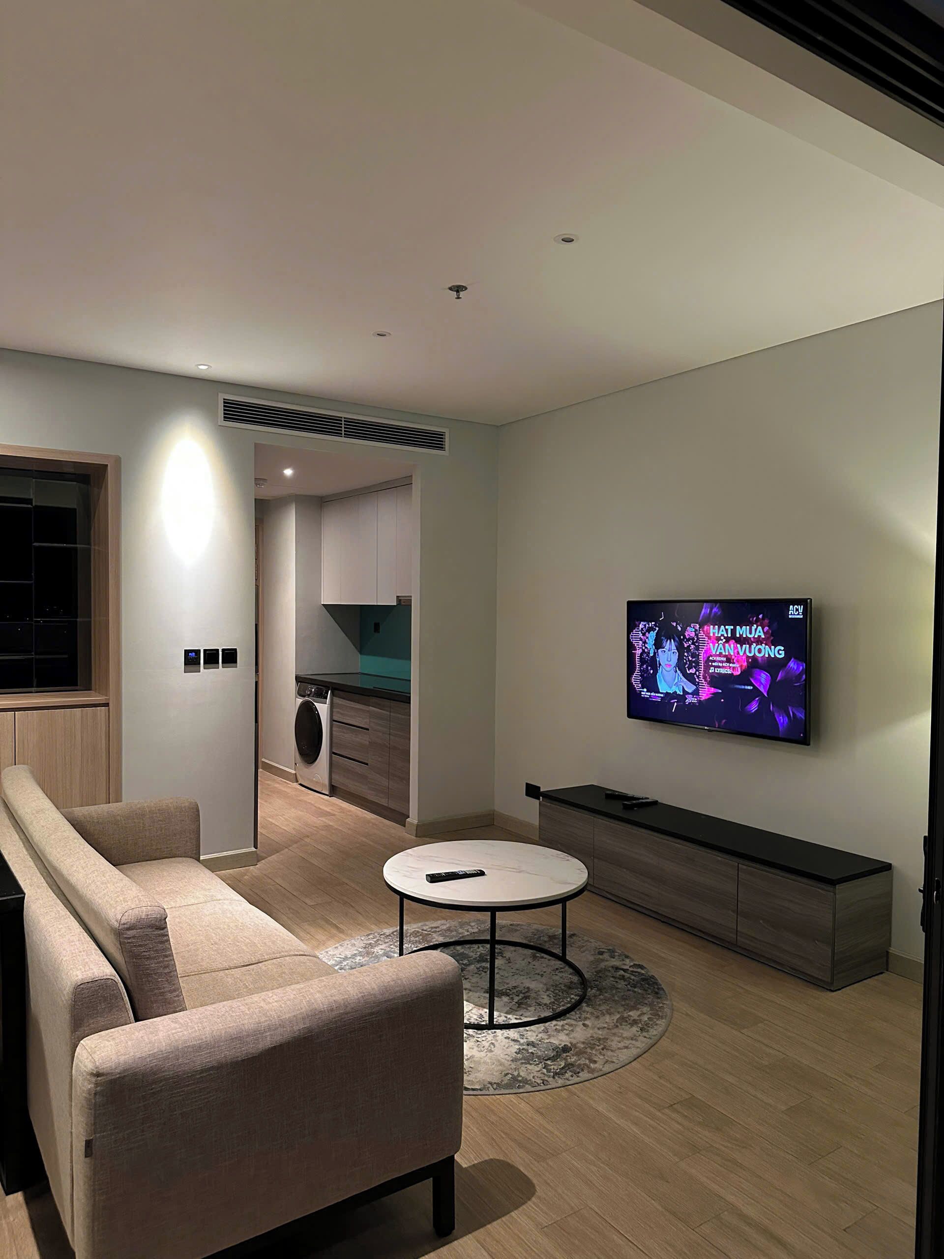 Ein modernes Wohnzimmer mit einer Couch, einem Couchtisch und einem an der Wand befestigten Fernseher.