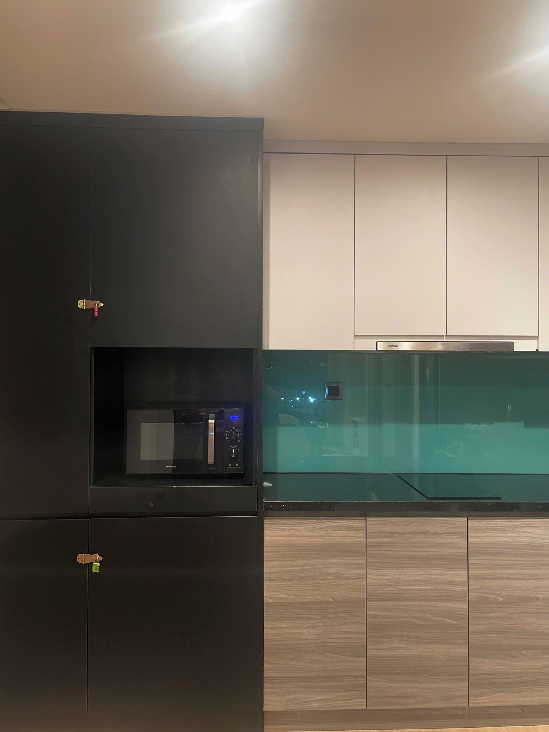 A modern kitchen with a built-in microwave, a stainless steel range hood, and wooden cabinetry.