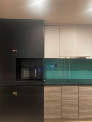 A modern kitchen with a built-in microwave, a stainless steel range hood, and wooden cabinetry. - CMH Homestay A side - 5star standard (Halong City)