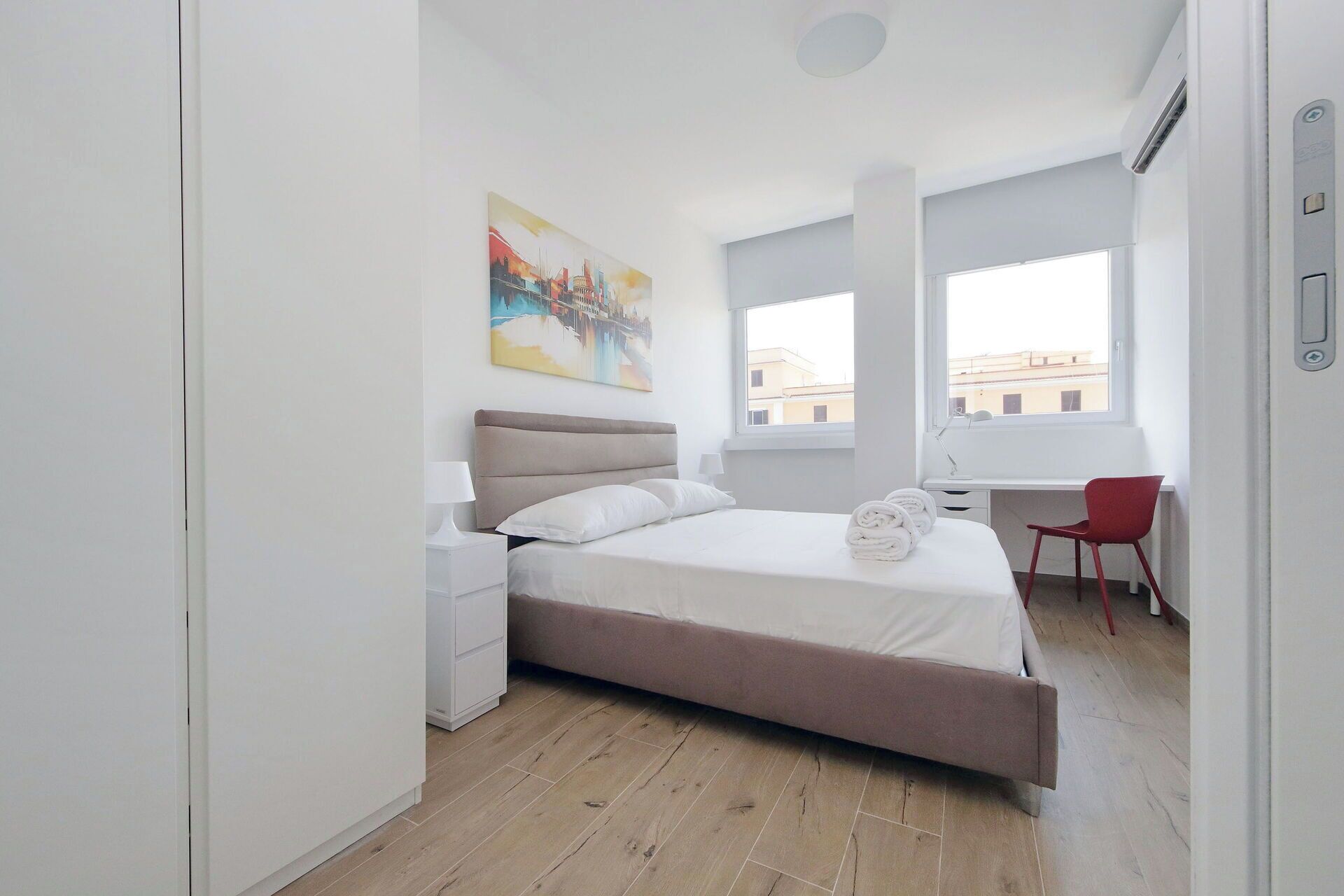 A modern bedroom with a bed, bedside table, and a desk with a chair.