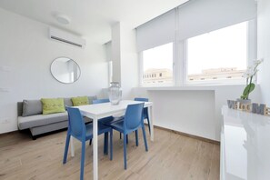 A modern living room with a white sofa, blue chairs, a white table, a round mirror, and a window with a view of buildings. - Apartment in Rome with 1 bedrooms sleeps 4 (Rome)