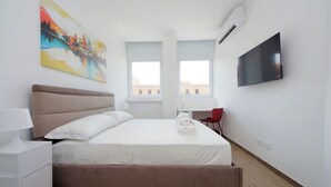 Een hotelkamer met een bed, een bureau, een stoel, een televisie en een schilderij aan de muur.