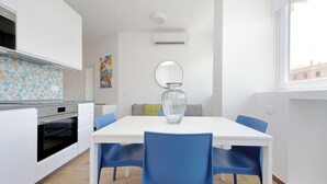Een moderne keuken met witte kastjes, een ingebouwde oven en een kleurrijke achterwand.