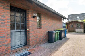 A brick building with a door, a window, and a trash bin area.