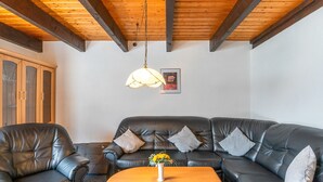 Una sala de estar con un sofá de cuero, una mesa de centro de madera y una lámpara colgante.