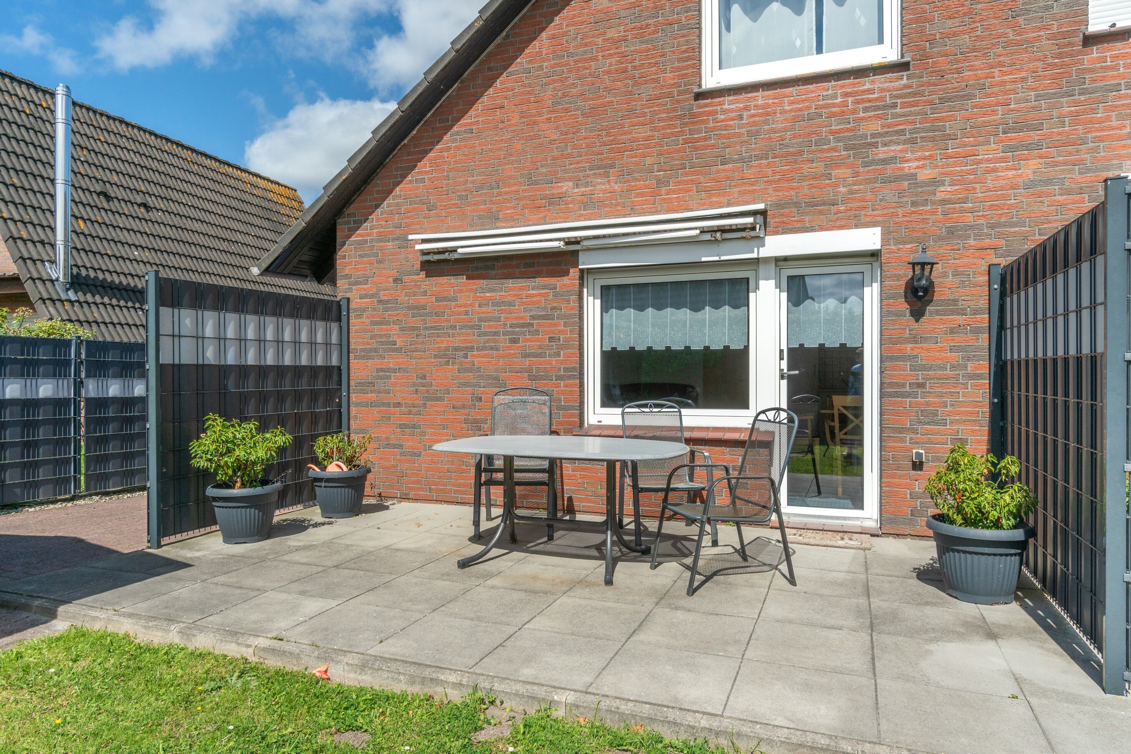 Een bakstenen huis met een terras, een tafel en stoelen.