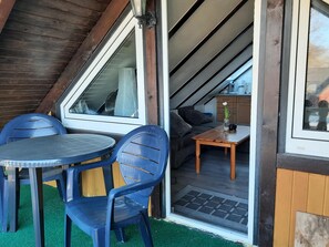 A small, cozy room with a wooden ceiling, a table with chairs, and a sofa. - Apartment 'FeWo 4 "Jan"' with Shared Garden (Dornum)