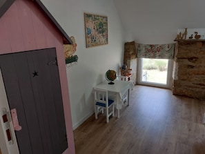 Ein Zimmer mit Holzboden, einem weißen Tisch mit Globus, einem Stuhl, einer rosafarbenen Wand, einem Gemälde und einem Fenster mit Blick.
