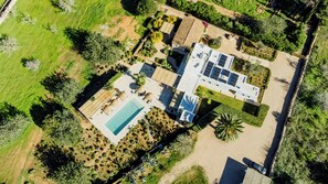 An aerial view of a property with a swimming pool, solar panels, and a garden.
