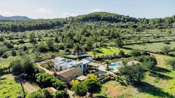 A residential property with a swimming pool, a garden, and a view of a forested area.