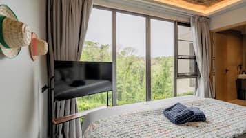A bedroom with a bed, a television, and a window with curtains.