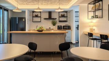 A modern kitchen with a central island, black chairs, and pendant lighting.