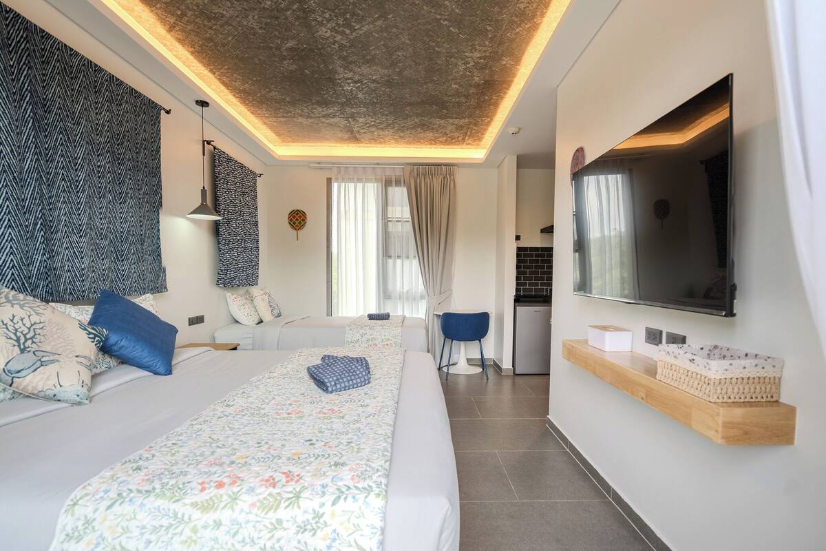 Family Triple Room with Kitchenette Street View | Cofres nos quartos, escrivaninha, ferros/tábuas de passar roupa