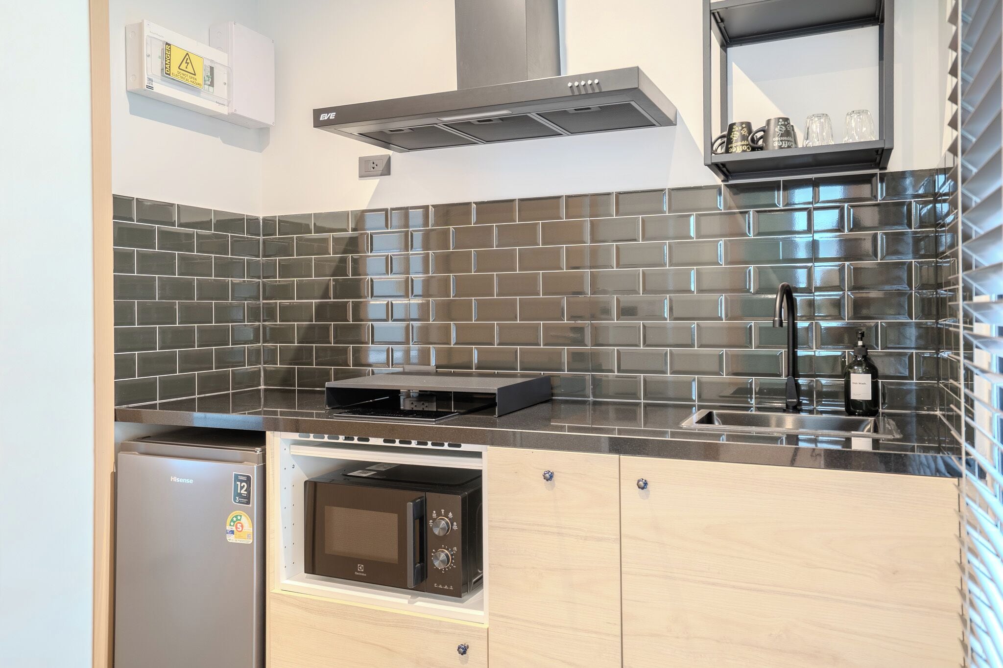 A compact kitchen with a stainless steel range, a built-in microwave, and a modern backsplash.