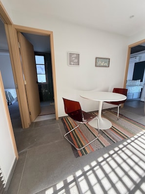 A dining area with a round table and two chairs, a patterned rug, and two wall-mounted signs.