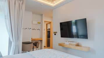 Habitación de hotel con cama, televisor montado en la pared, un pequeño escritorio con silla y un baño visible a través de una puerta abierta.