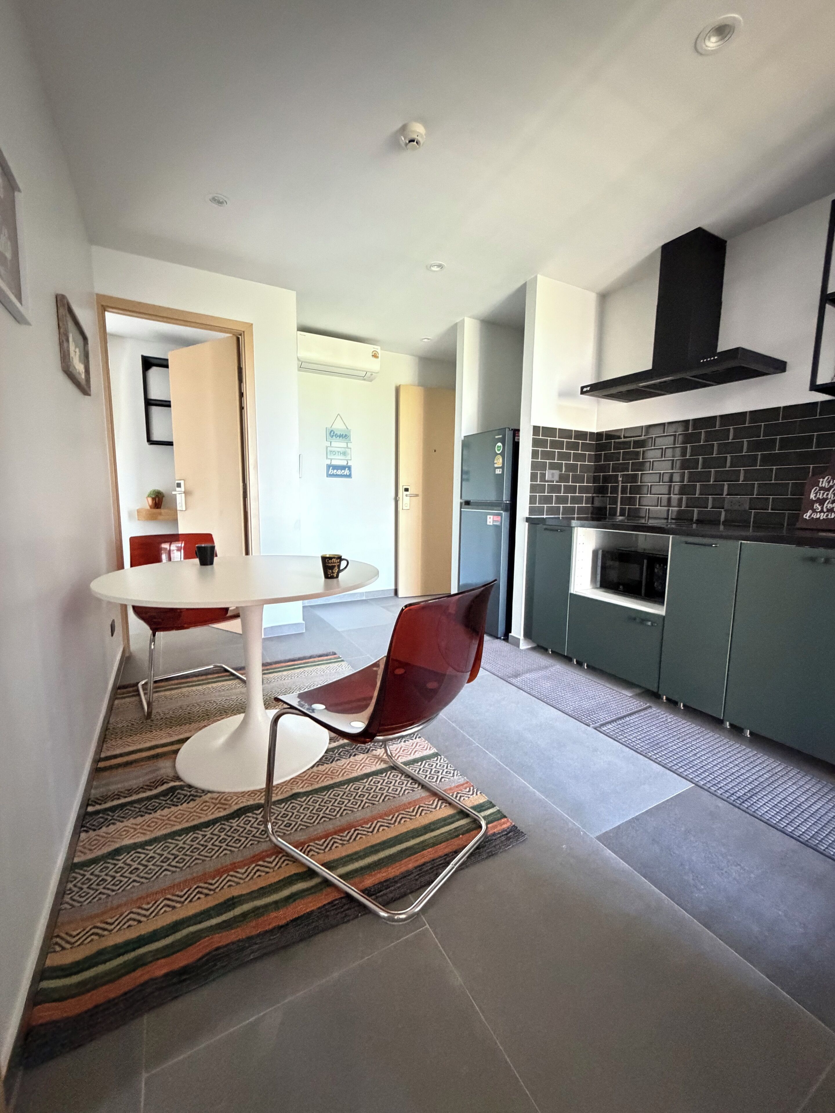 A modern kitchen with a black tiled backsplash, a built-in oven, and a stainless steel refrigerator.