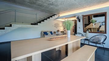 Un interior moderno con una mesa de comedor de madera, un sofá y una escalera.