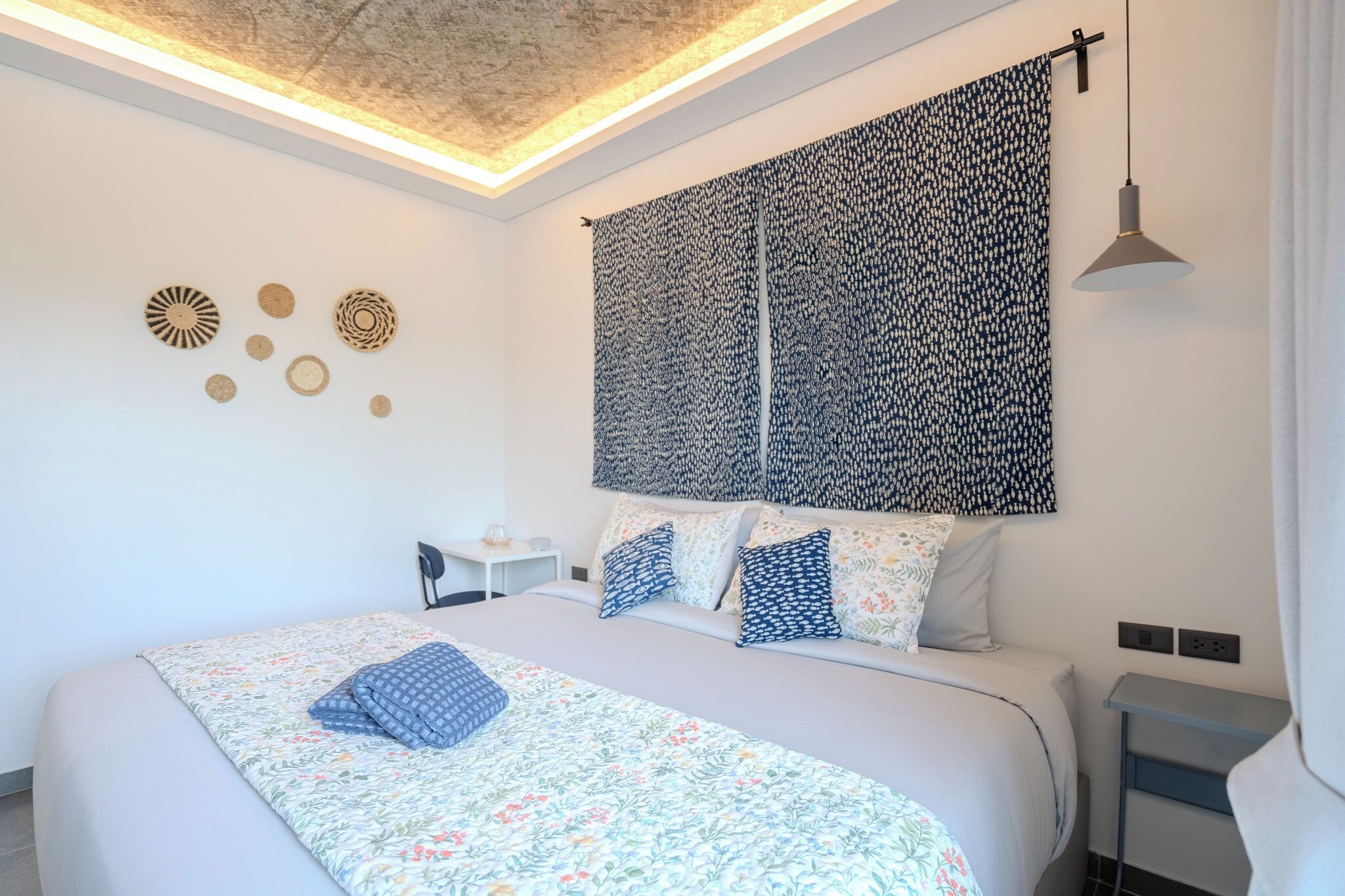 Un dormitorio moderno con una cama grande, un escritorio y un tapiz colgado en la pared.