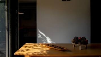 A room with a wooden table, a bowl of fruit, and a projector screen.