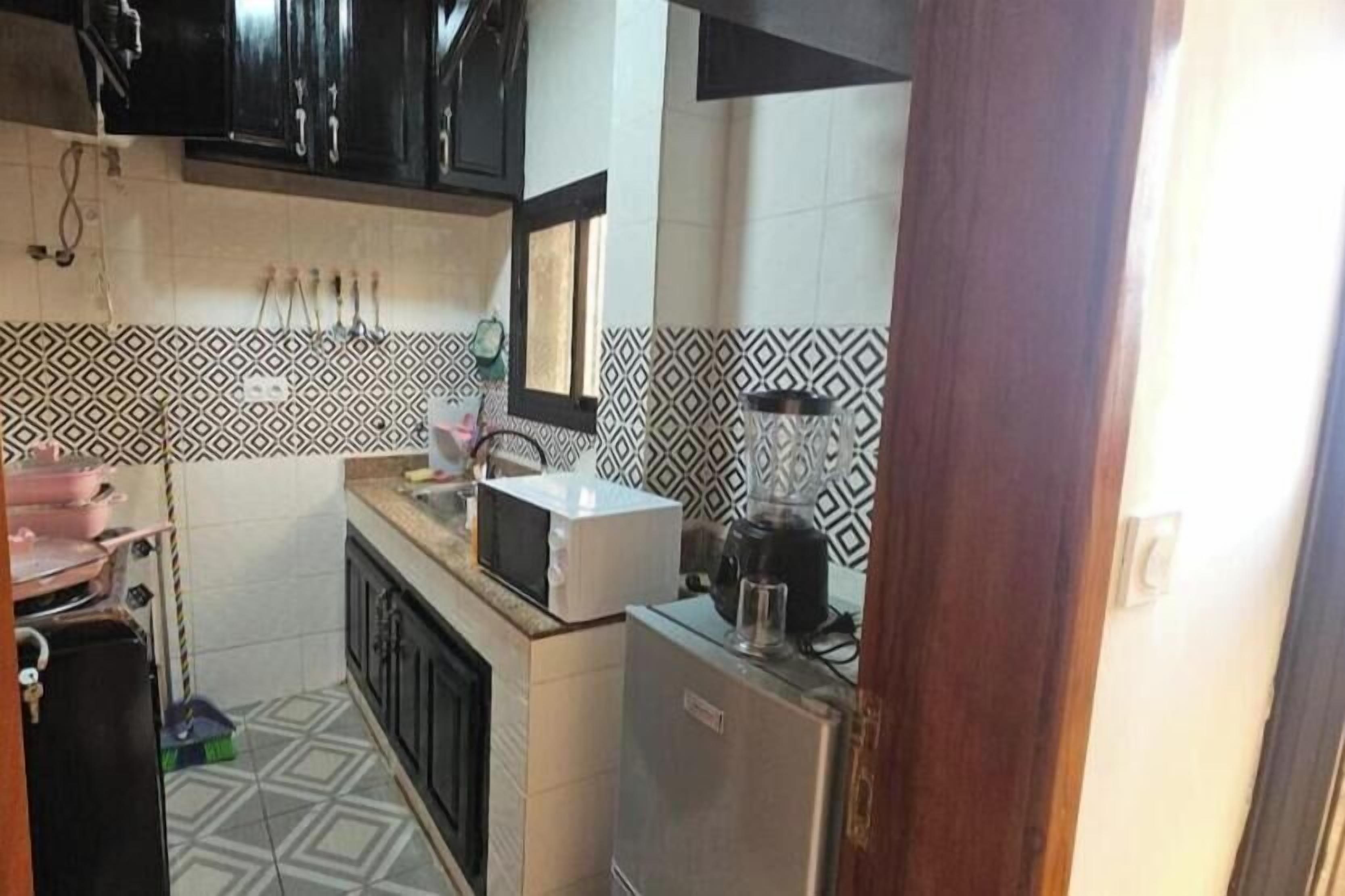 Una cocina compacta con microondas, refrigerador y pileta.