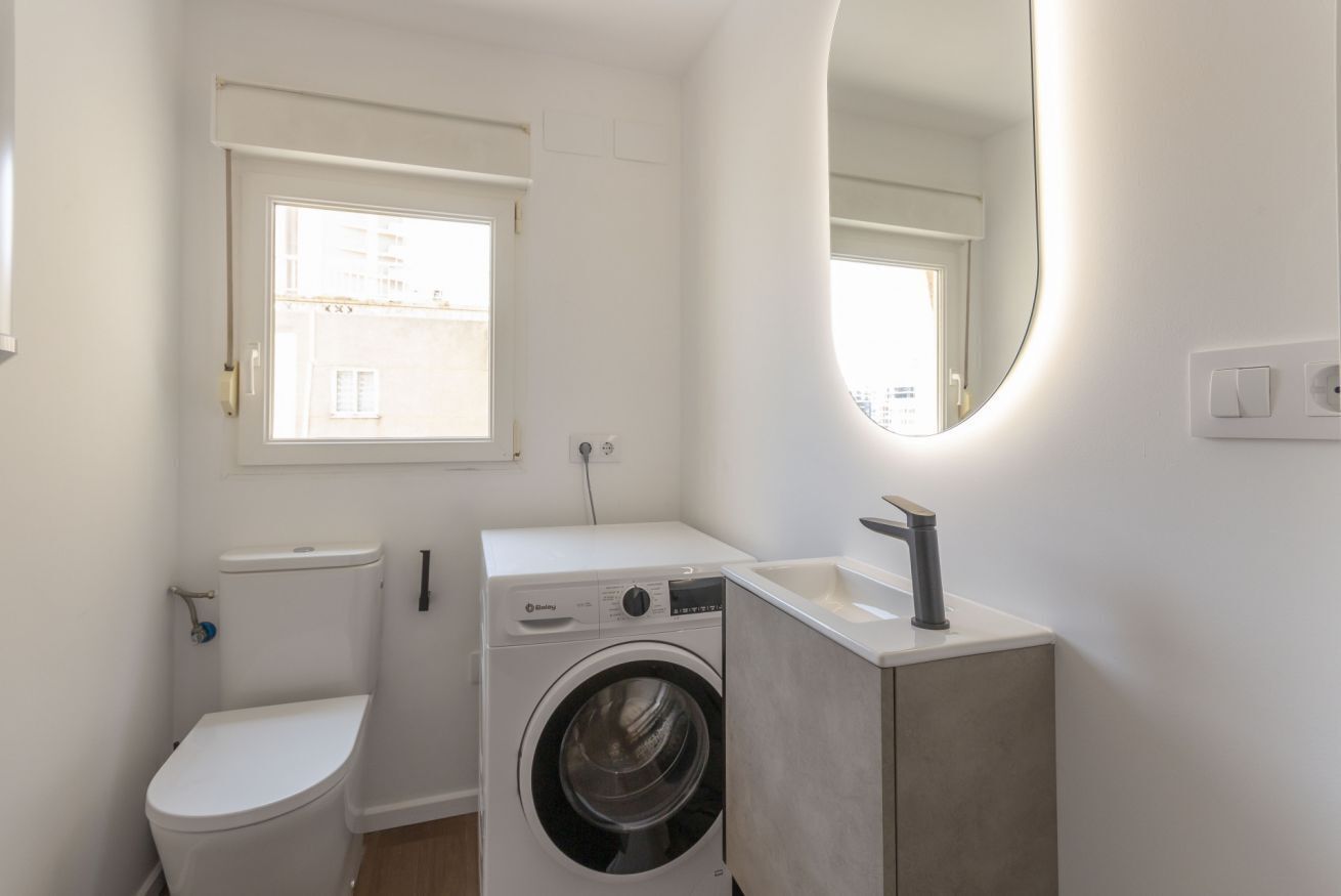 A compact bathroom with a toilet, washing machine, and sink.