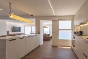 A modern kitchen with a central island, built-in appliances, and a view to the outside. - Your beachfront home in Calpe: the perfect retreat for every season.Imagine waking up every morning to the golden Mediterranean light flooding your home, gazing at the breathtaking silhouette of the Peñón de Ifach while enjoying a peaceful coffee on yo (Calp)