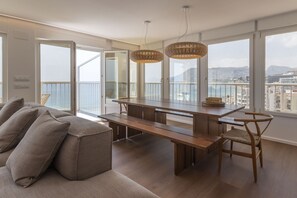 Ein modernes Wohnzimmer mit großem Esstisch, bequemen Sitzgelegenheiten und großen Fenstern mit Blick auf die Stadt.