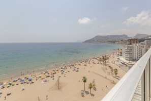 A beach with umbrellas and people, a clear sky, and buildings in the background. - Your beachfront home in Calpe: the perfect retreat for every season.Imagine waking up every morning to the golden Mediterranean light flooding your home, gazing at the breathtaking silhouette of the Peñón de Ifach while enjoying a peaceful coffee on yo (Calp)