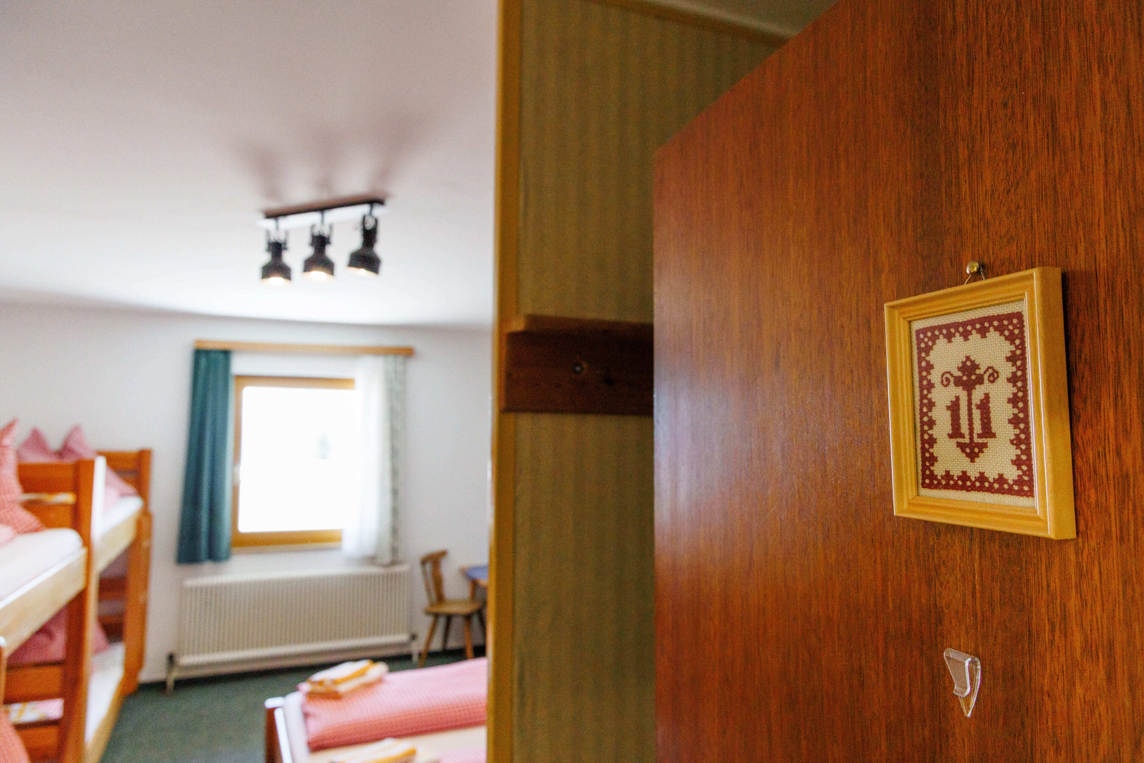 Une chambre avec des lits superposés, un tableau encadré au mur et une fenêtre avec des rideaux.