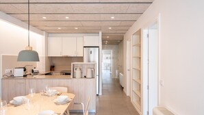 A modern kitchen with a dining area, featuring a central island, built-in cabinets, and a pendant light. - Majordoms Llimoner 1 - Figueres (Figueres)