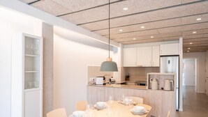 A modern kitchen with a central island, white cabinetry, and a dining area set for six with a table, chairs, and dinnerware. - Majordoms Llimoner 1 - Figueres (Figueres)