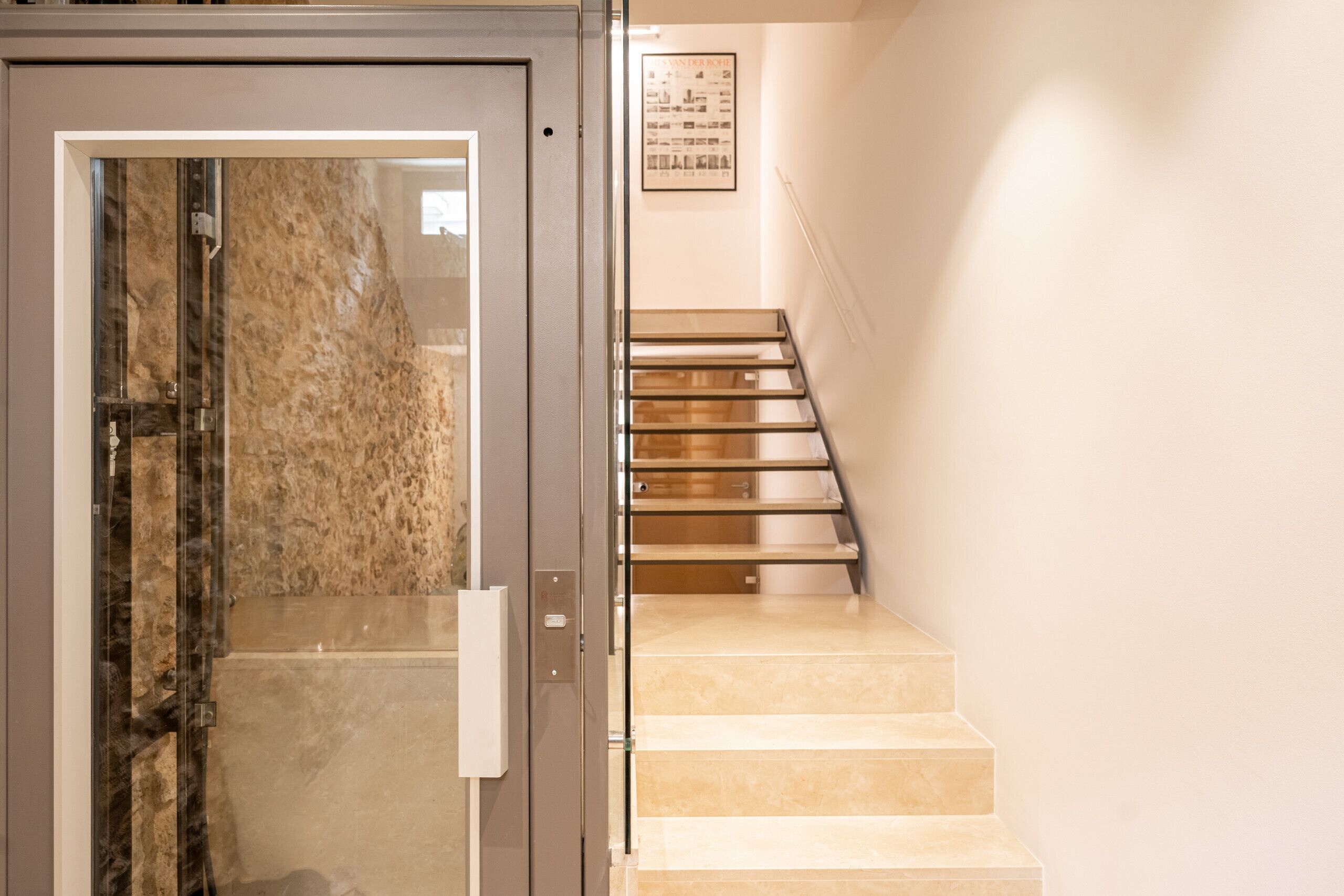 Una escalera con barandilla y una puerta con panel de vidrio.