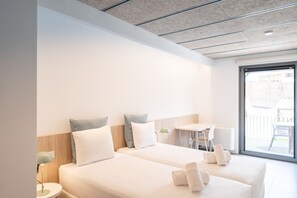 Une chambre d’hôtel moderne avec deux lits, une petite table, une chaise et une vue sur l’extérieur.